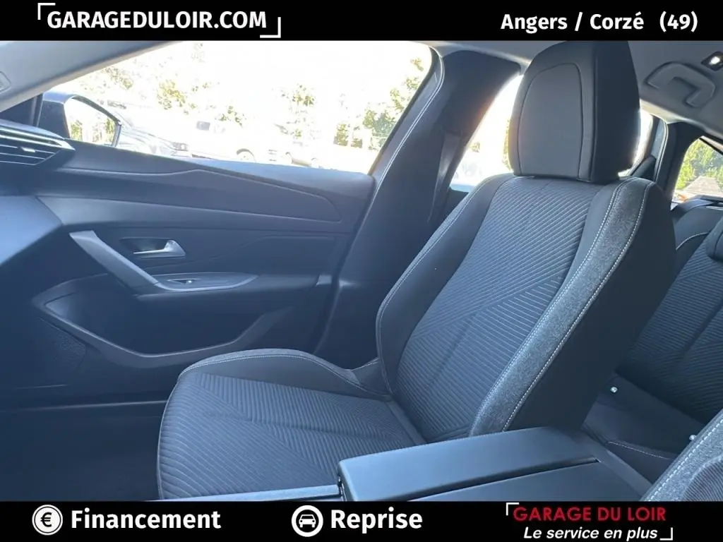 Vue intérieure côté passager avant du Peugeot 308 gris clair 2023, sièges tissu avec surpiqûres contrastées.