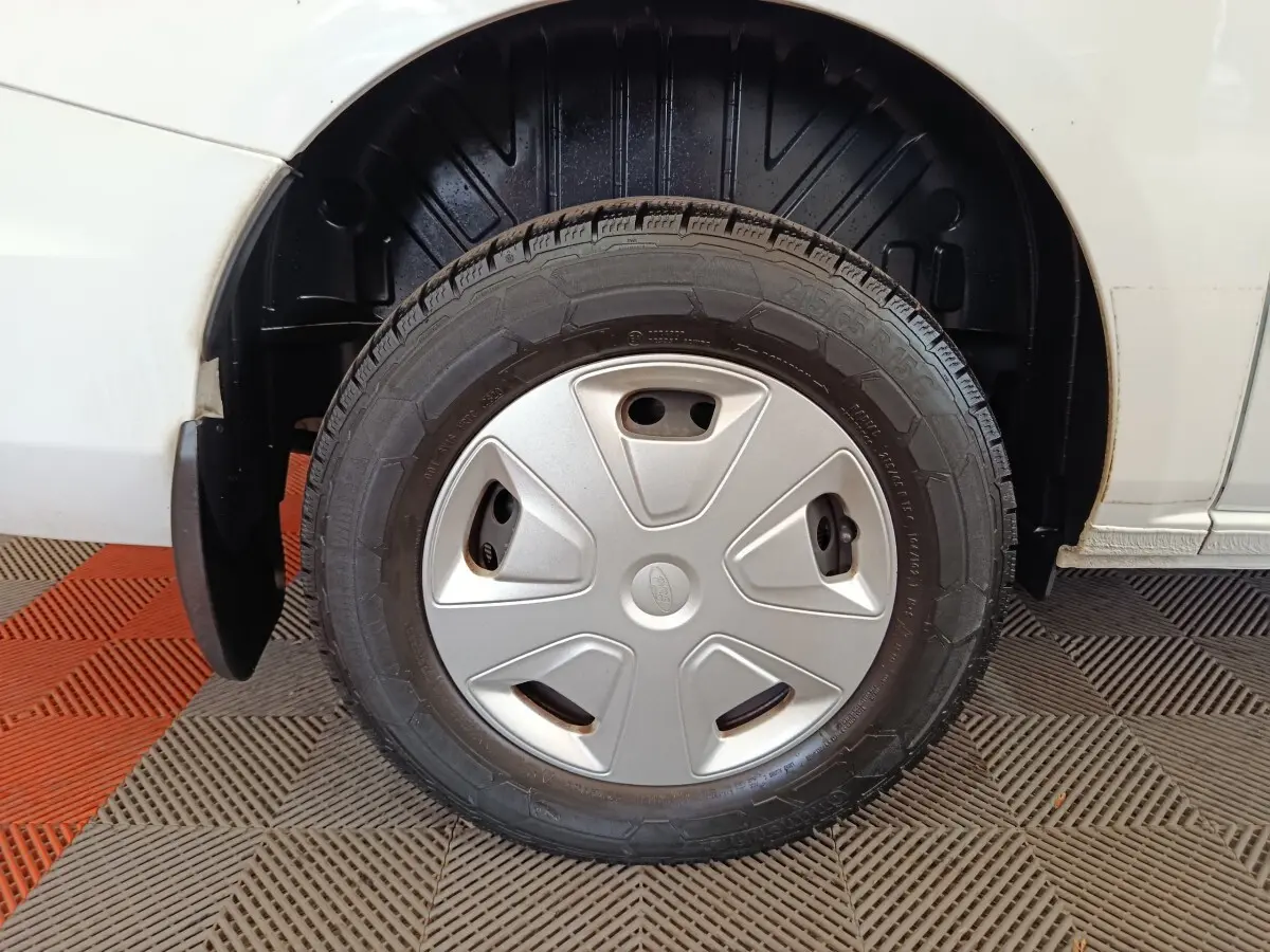 Gros plan sur la roue avant droite du Ford Transit Custom blanc, avec enjoliveur gris et pneu visible.
