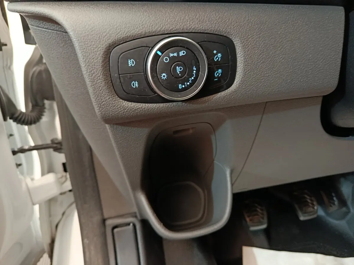 Gros plan sur le bouton de réglage des phares du Ford Transit Custom blanc, intérieur côté conducteur.