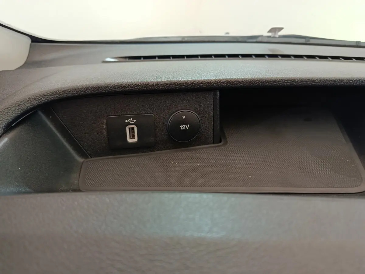 Gros plan sur la prise USB et la prise 12V intégrées dans la console centrale du Ford Transit Custom blanc.