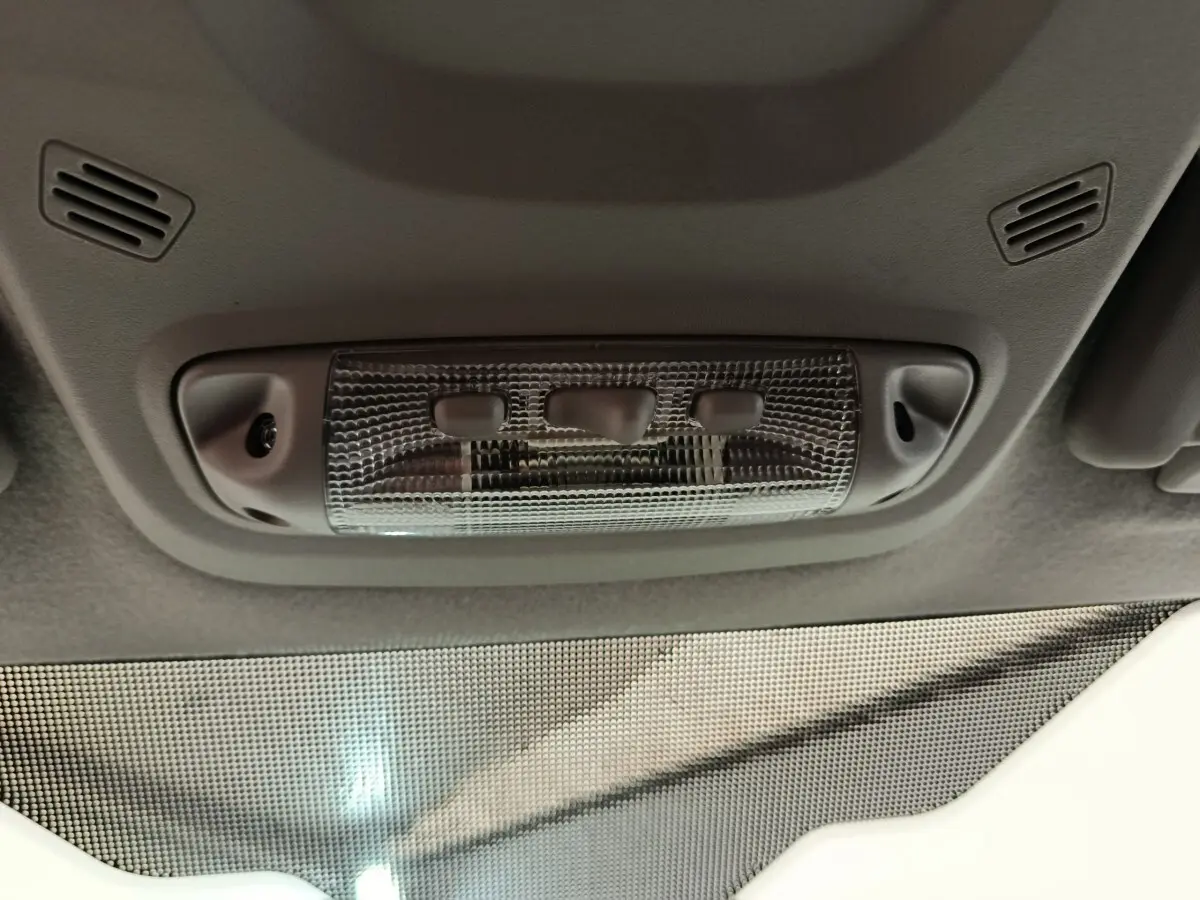 Plafonnier intérieur gris avec trois boutons, visible depuis l’habitacle du Ford Transit Custom blanc.