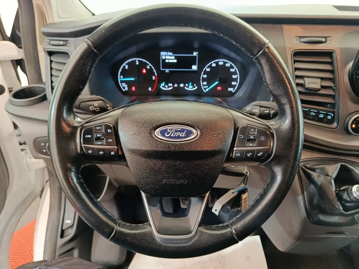 Vue rapprochée du volant en cuir noir et du tableau de bord digital du Ford Transit Custom blanc de 2020.