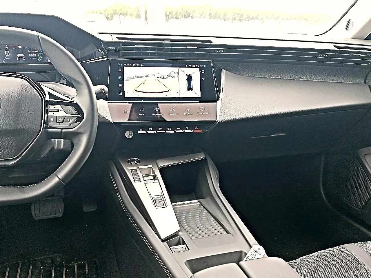 Vue intérieure du tableau de bord et console centrale de la Peugeot 408 Hybrid 145 allure gris sellenium avec écran tactile affichant la caméra de recul.