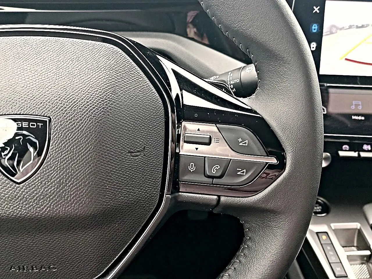 Gros plan sur le volant cuir noir multifonction de la Peugeot 408 Hybrid 145 allure 2024 avec commandes audio et vocales.