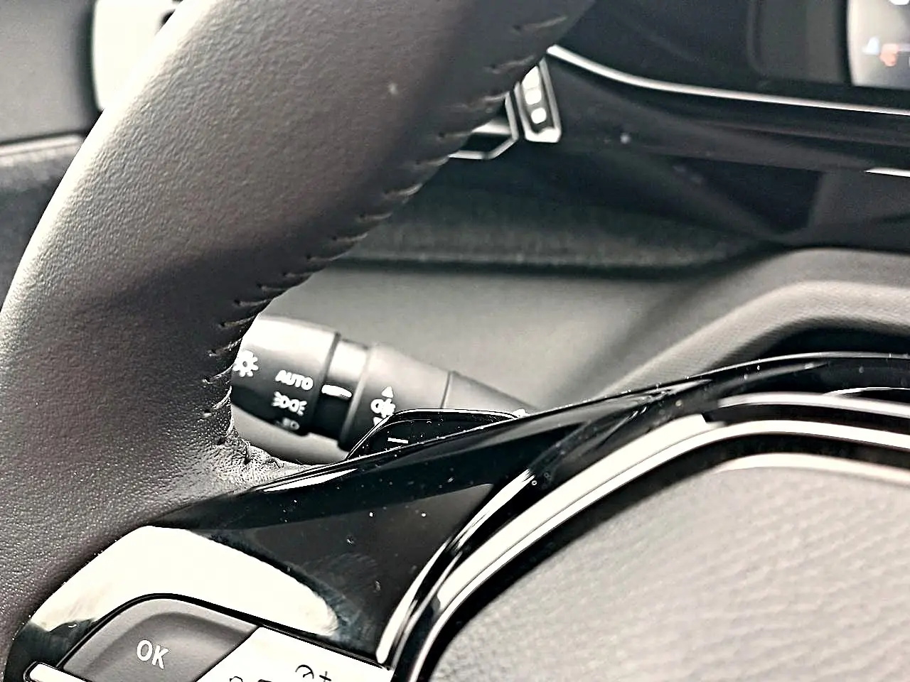 Gros plan sur le volant cuir noir multifonction de la Peugeot 408 Hybrid 145 allure 2024, avec commandes intégrées.