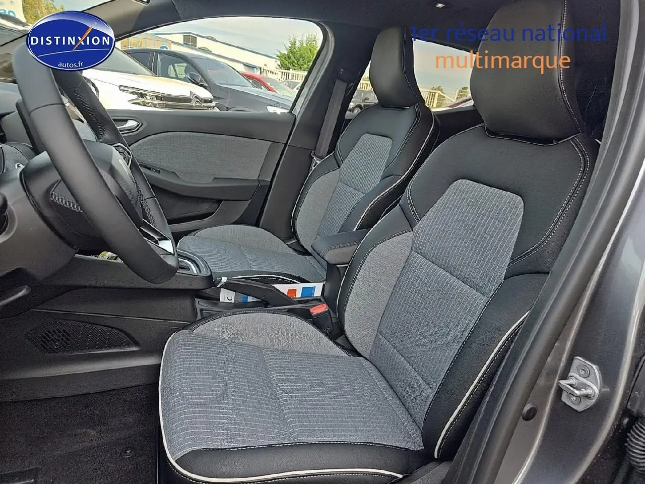 Intérieur de la Renault Clio V gris schiste, vue côté droit sur les sièges avant en tissu bicolore avec surpiqûres blanches.