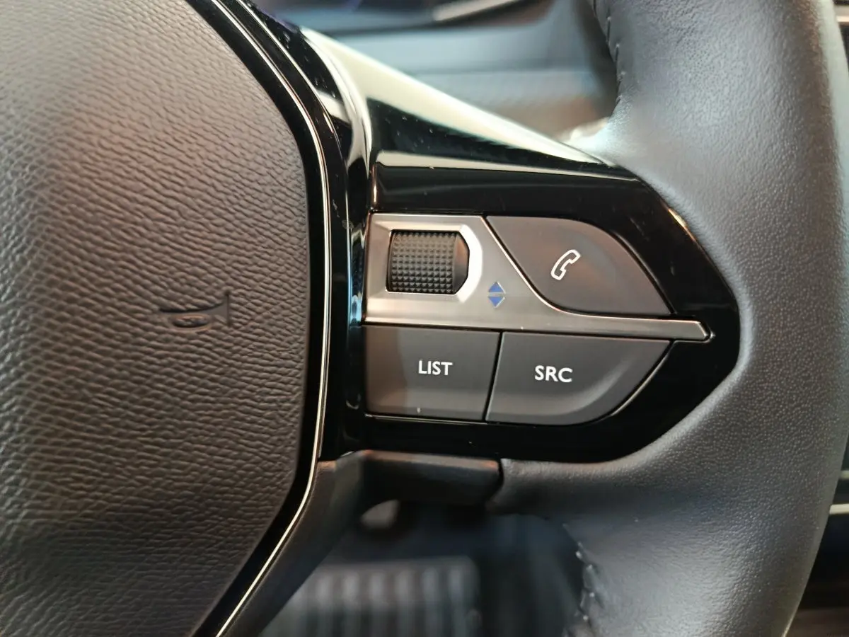 Gros plan sur les commandes du volant cuir à droite de la Peugeot 208 PureTech 100 S&S Allure 2025.