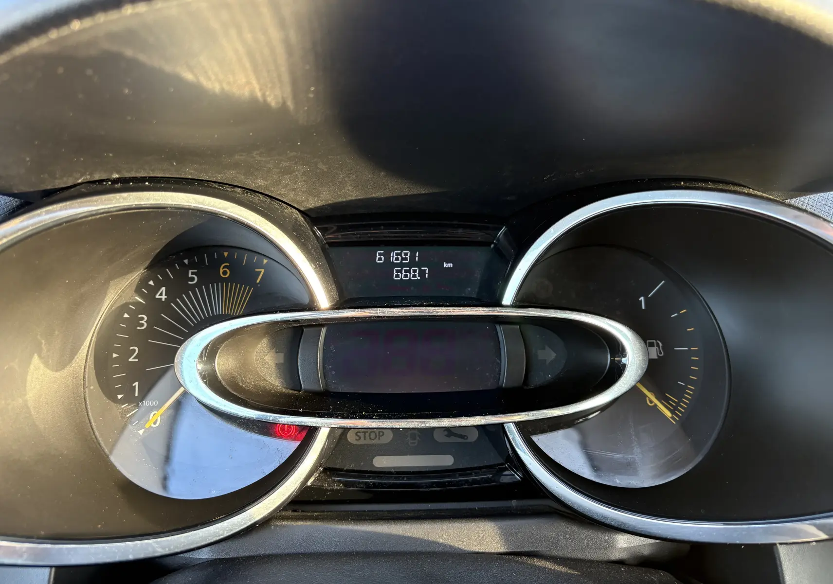 Vue rapprochée du tableau de bord de la Renault Clio IV gris, affichant compte-tours, jauge carburant et kilométrage.