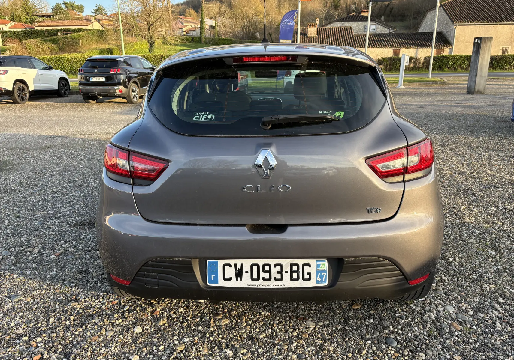 Vue arrière d'une Renault Clio IV gris métallisé de 2013 avec logo et plaques françaises visibles sur un parking extérieur.