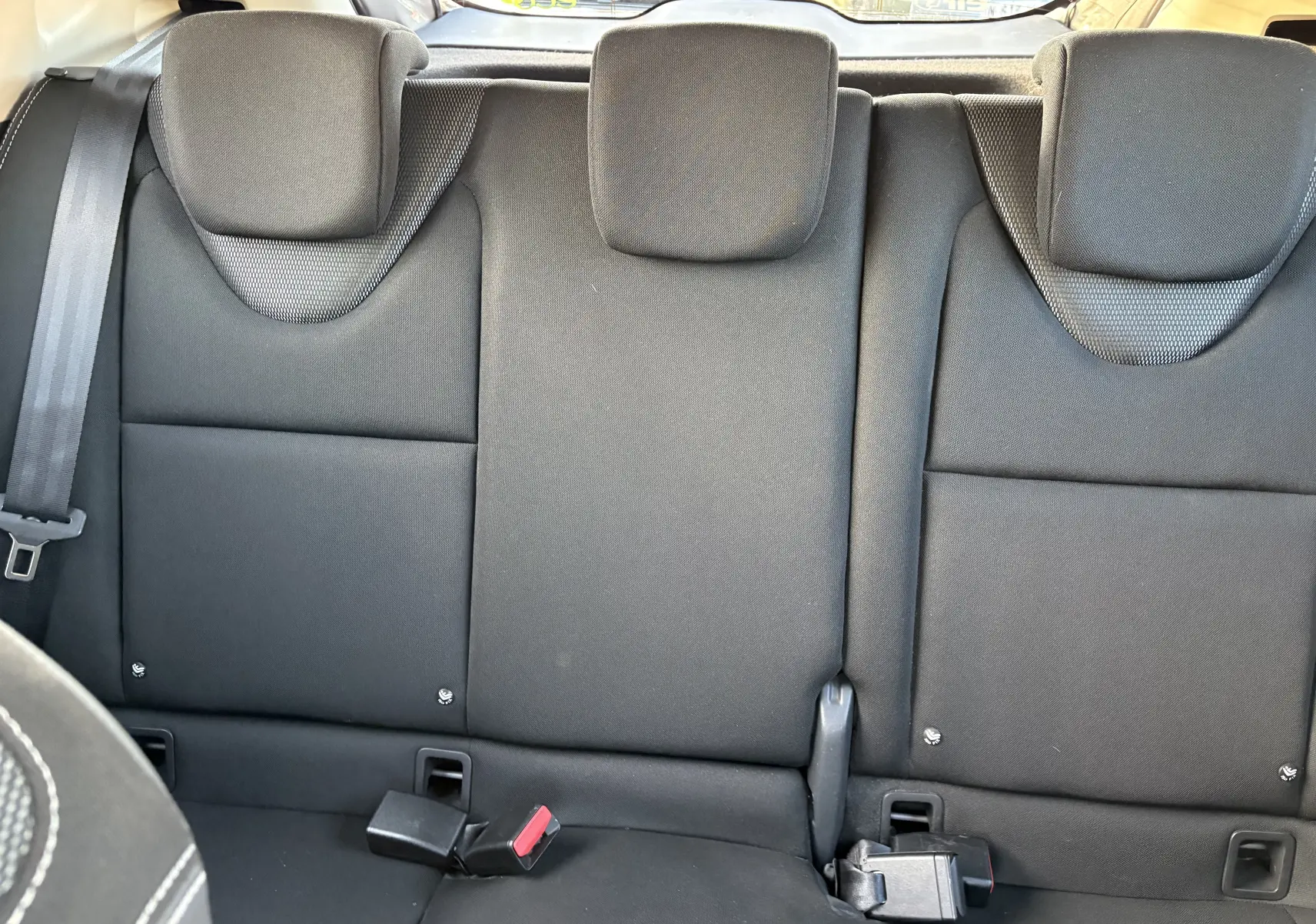 Vue intérieure sur la banquette arrière noire de la Renault Clio IV Phase 1, avec ceintures de sécurité visibles.