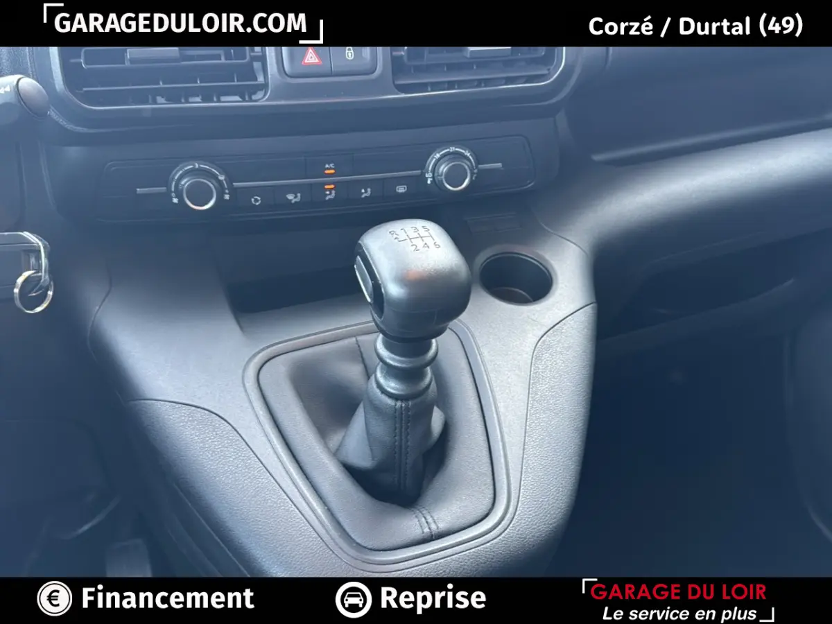 Gros plan sur le levier de vitesse manuel du Peugeot Rifter bleu 2024, avec commandes de climatisation en arrière-plan.