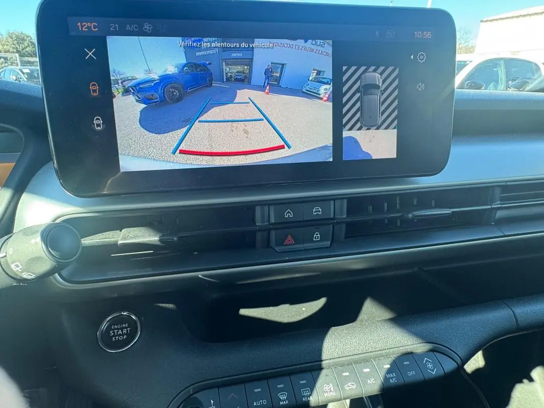 Vue intérieure du tableau de bord du Jeep Avenger gris 2025, écran tactile affichant la caméra de recul et commandes climatisation.