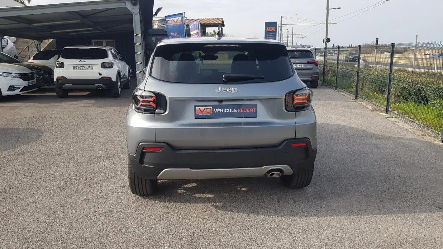 Vue arrière d’un Jeep Avenger gris 2025 avec feux arrière LED et plaque « Véhicule récent » visible.