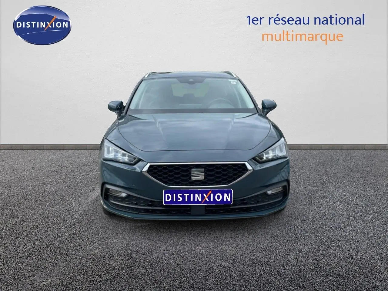 Vue de face d'une SEAT LEON ST 2.0 TDI bleu fjord avec calandre hexagonale et phares LED allumés.