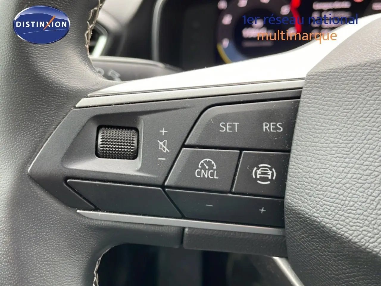 Gros plan sur les commandes de régulateur de vitesse au volant d’un SEAT LEON ST 2.0 TDI 115CH STYLE XL, intérieur gris-noir.
