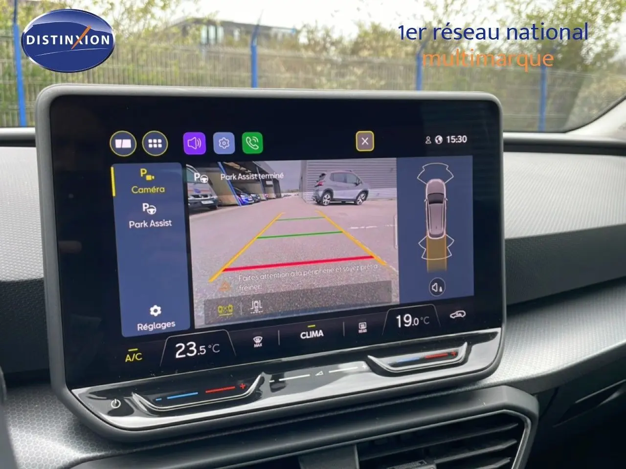 Écran central tactile affichant la caméra de recul et l'assistance au stationnement dans un SEAT Leon ST bleu Fjord.