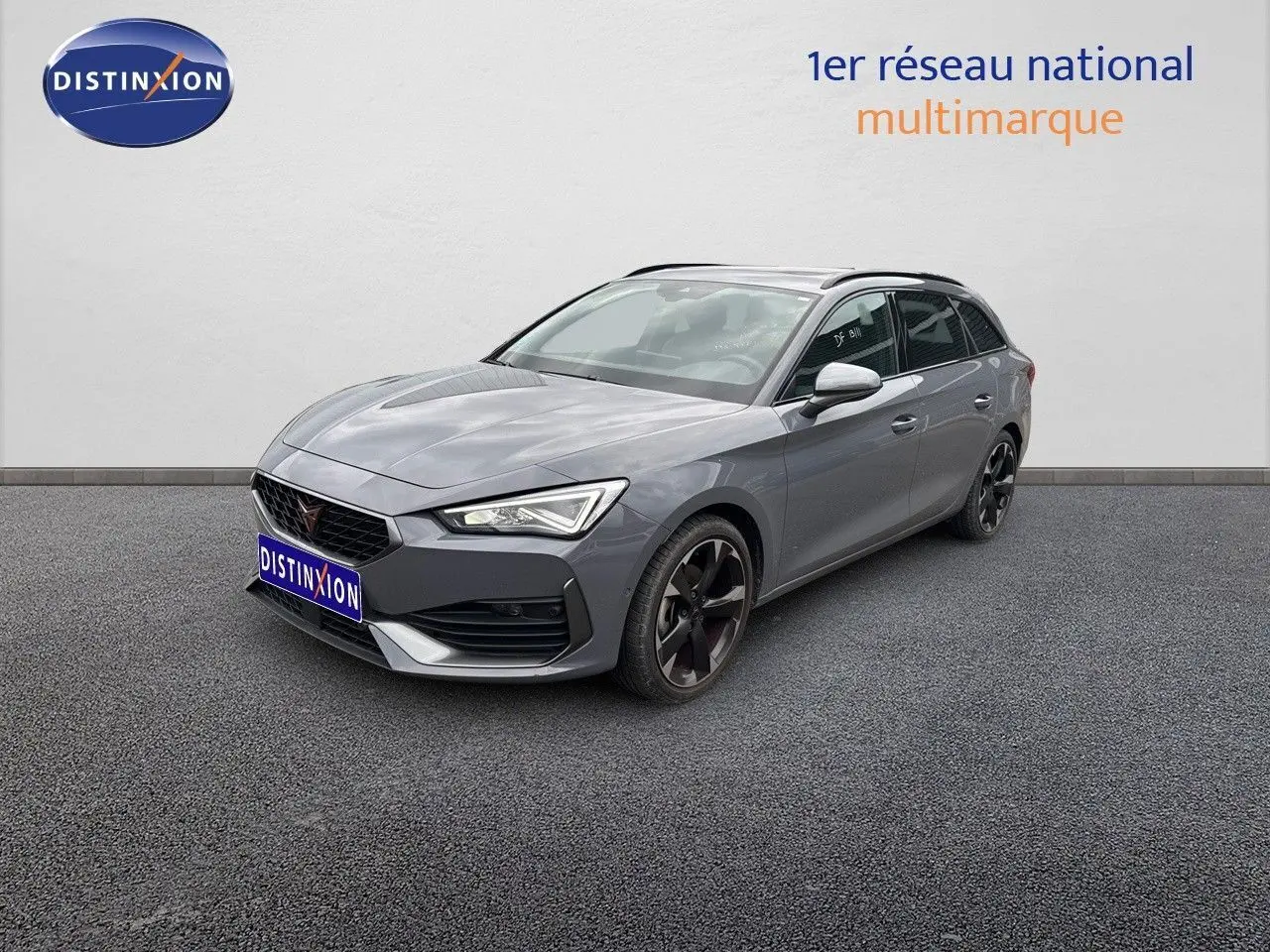 Vue 3/4 avant droite d'une CUPRA LEON ST gris Graphene avec jantes noires et calandre distinctive.