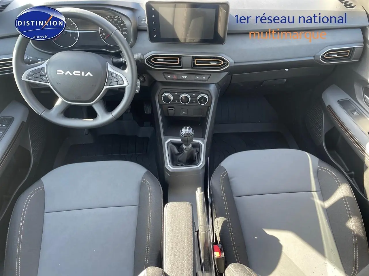 Vue intérieure de la Dacia Sandero 2025 avec tableau de bord, volant multifonction et sièges gris schiste.