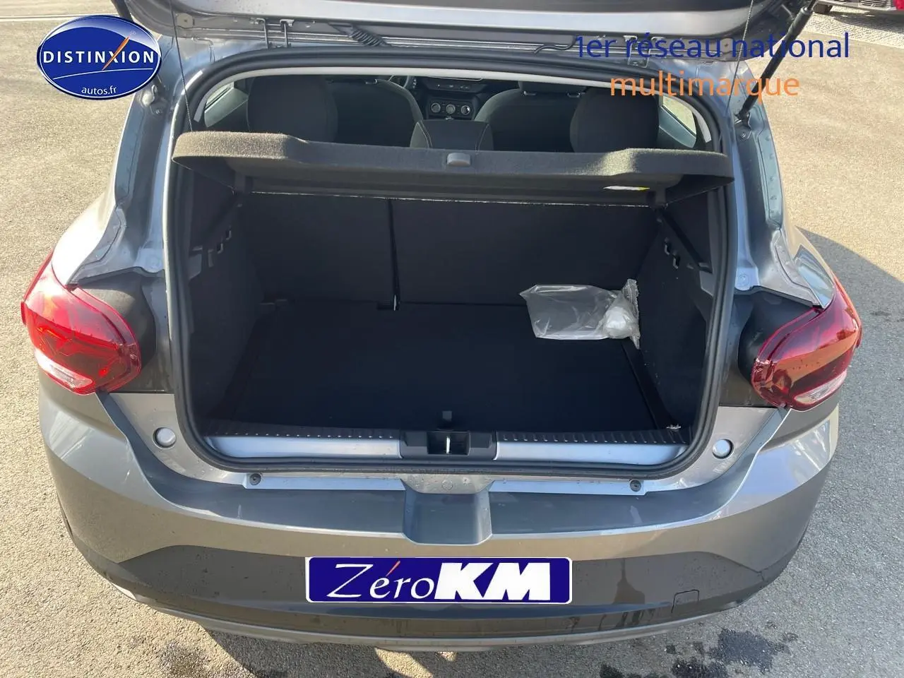 Coffre ouvert d'une Dacia Sandero gris schiste vue de l'arrière, montrant l'espace de chargement vide.