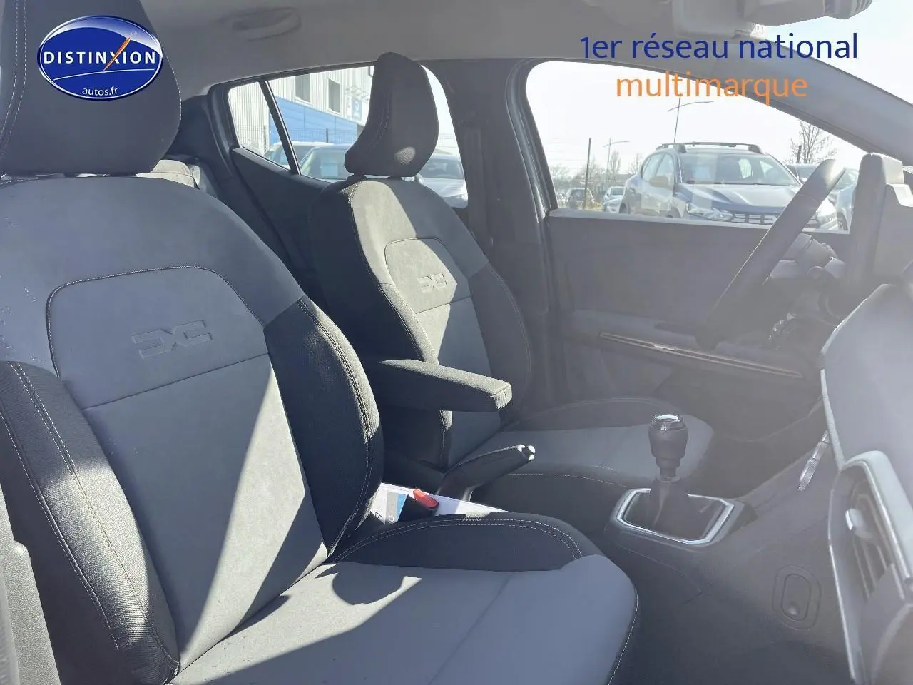 Intérieur avant de la Dacia Sandero Stepway 2025, sièges gris avec accoudoir central et levier de vitesse manuel visible.