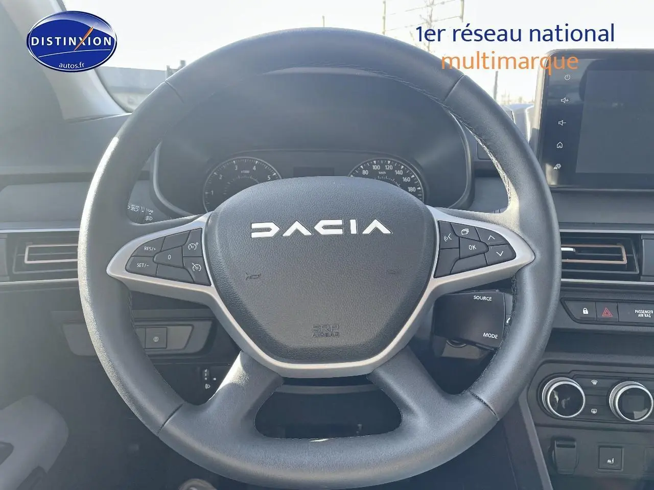 Volant noir avec logo DACIA en vue frontale, tableau de bord et écran tactile visibles dans l'habitacle d'une Sandero 2025