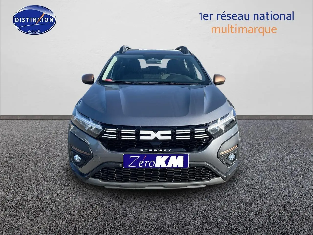 Vue frontale d'une Dacia Sandero Stepway gris schiste avec calandre noire et barres de toit visibles.