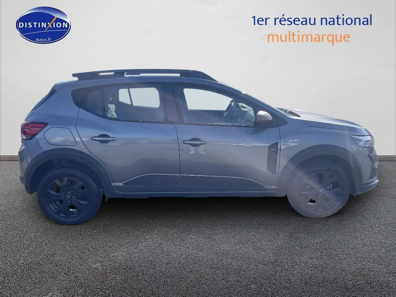 Profil côté gauche d'une Dacia Sandero Stepway gris schiste 2025 avec barres de toit et jantes alu noires.