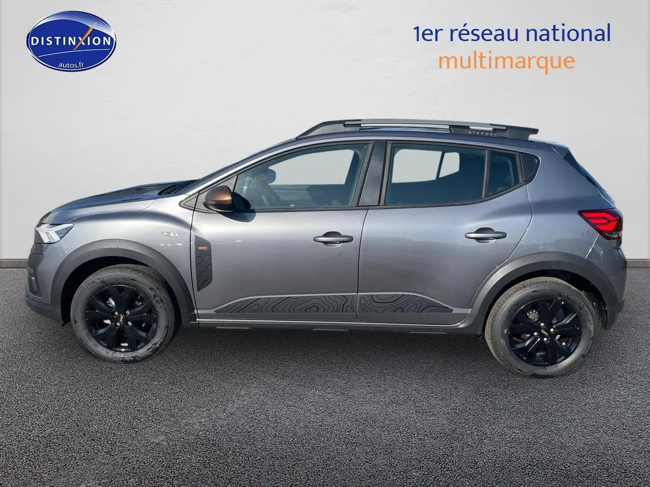 Profil côté gauche de la Dacia Sandero Stepway gris schiste avec jantes noires et barres de toit visibles