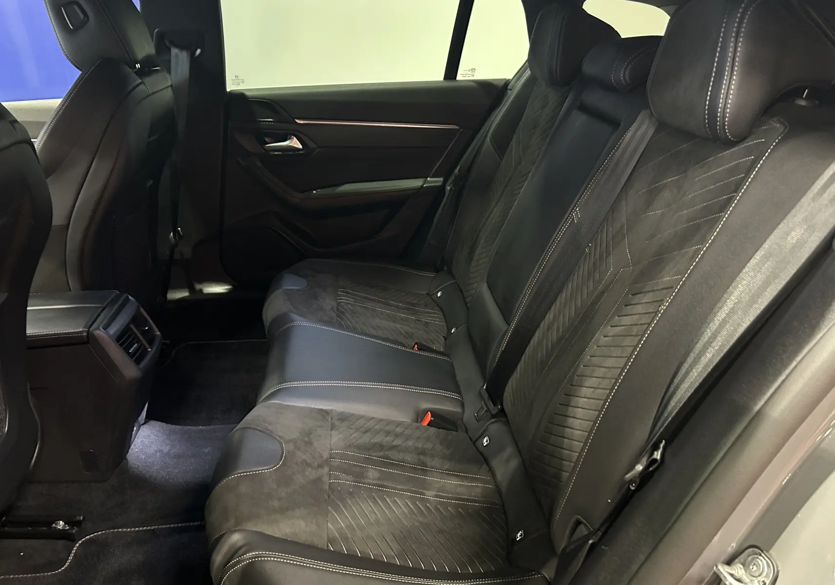 Vue latérale intérieure des sièges arrière en cuir noir et alcantara de la Peugeot 508 SW 2024 gris Selenium.