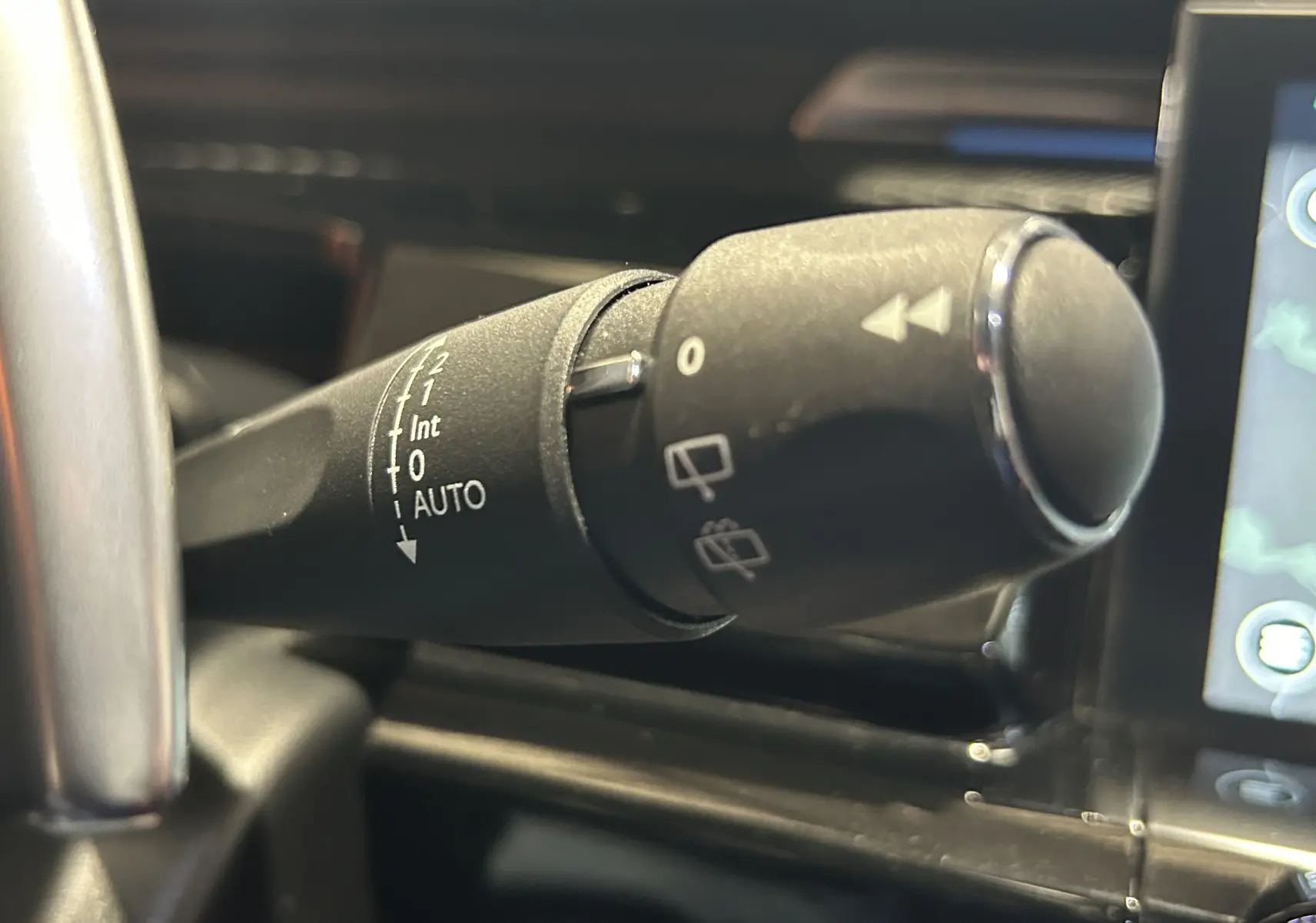 Gros plan sur la commande d'essuie-glace à gauche du volant dans l'habitacle d'une Peugeot 508 SW 2024.