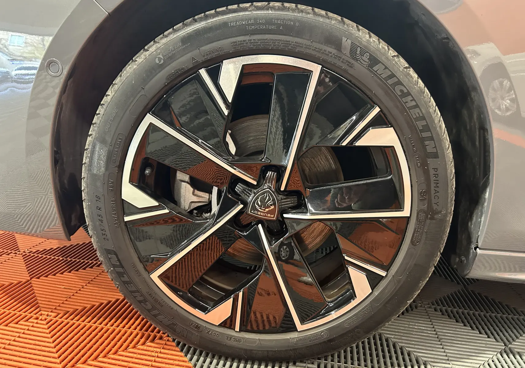 Gros plan sur la roue avant droite d'une Peugeot 508 SW gris Selenium avec jante alliage noire et argentée.