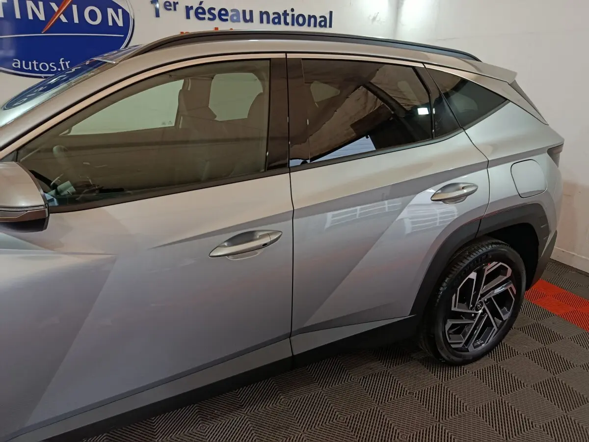 Vue latérale droite du Hyundai Tucson 1.6 Hybrid gris clair, soulignant les lignes anguleuses et les jantes distinctives.
