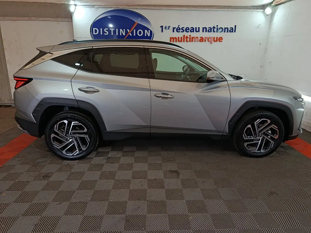 Vue de profil côté gauche du Hyundai Tucson 1.6 Hybrid 239 Creative Auto gris clair dans un garage.