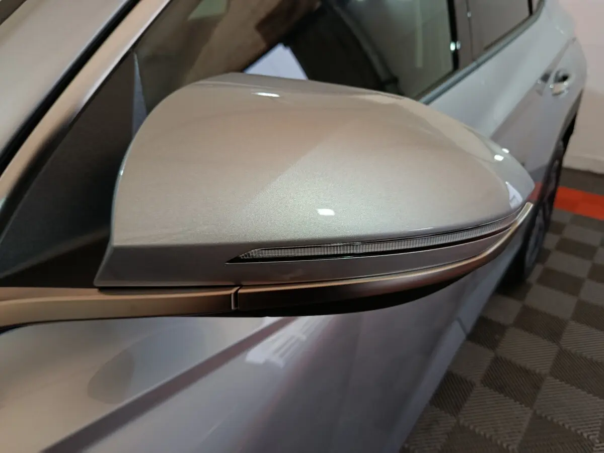Gros plan sur le rétroviseur droit gris clair du Hyundai Tucson 2025 avec clignotant intégré, vue latérale partielle.