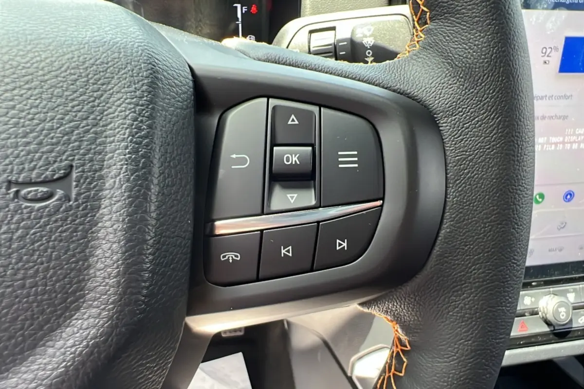 Gros plan sur les commandes multifonctions à droite du volant cuir noir avec surpiqûres orange du Ford Ranger Wildtrak 2026.