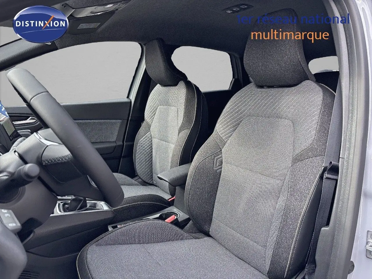 Vue intérieure côté gauche du Renault Captur II 1.6 E-Tech hybride 2025, sièges tissu gris avec accoudoir central.