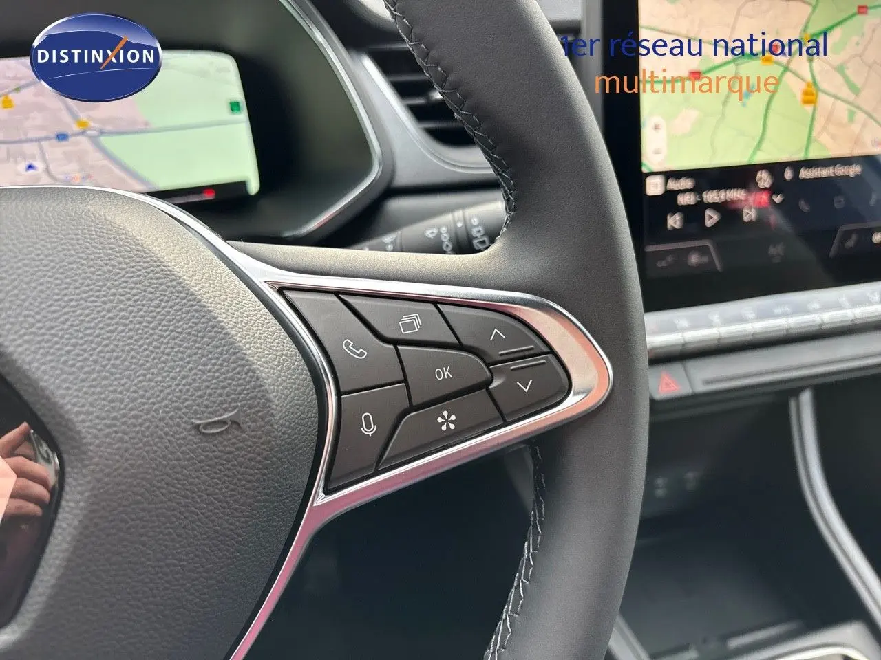 Gros plan sur le volant côté droit du Renault Captur 2025, avec commandes intégrées et écran tactile de navigation en arrière-plan.