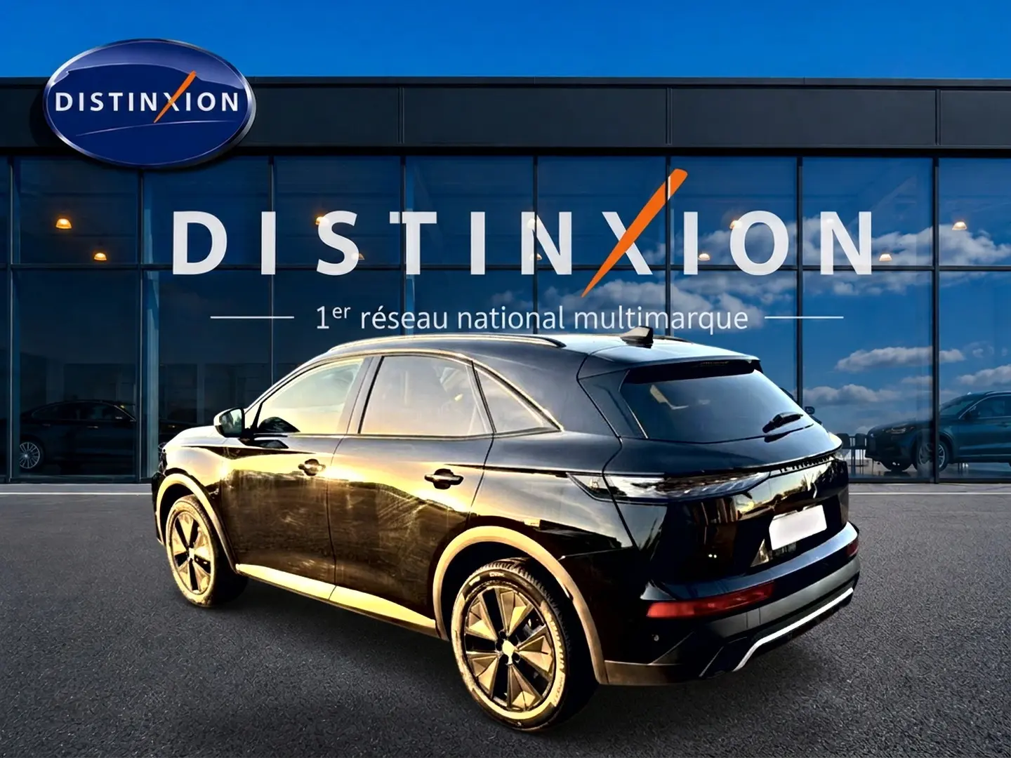 DS7 noir vue 3/4 arrière droit, avec jantes alliage et vitres arrière surteintées, stationné devant un showroom Distinxion.