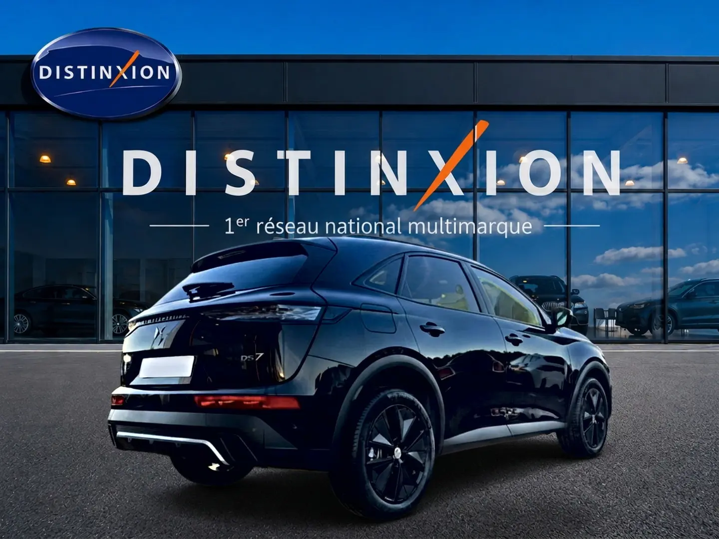 Vue 3/4 arrière droite d'un DS7 noir brillant garé devant une vitrine avec logo Distinxion.