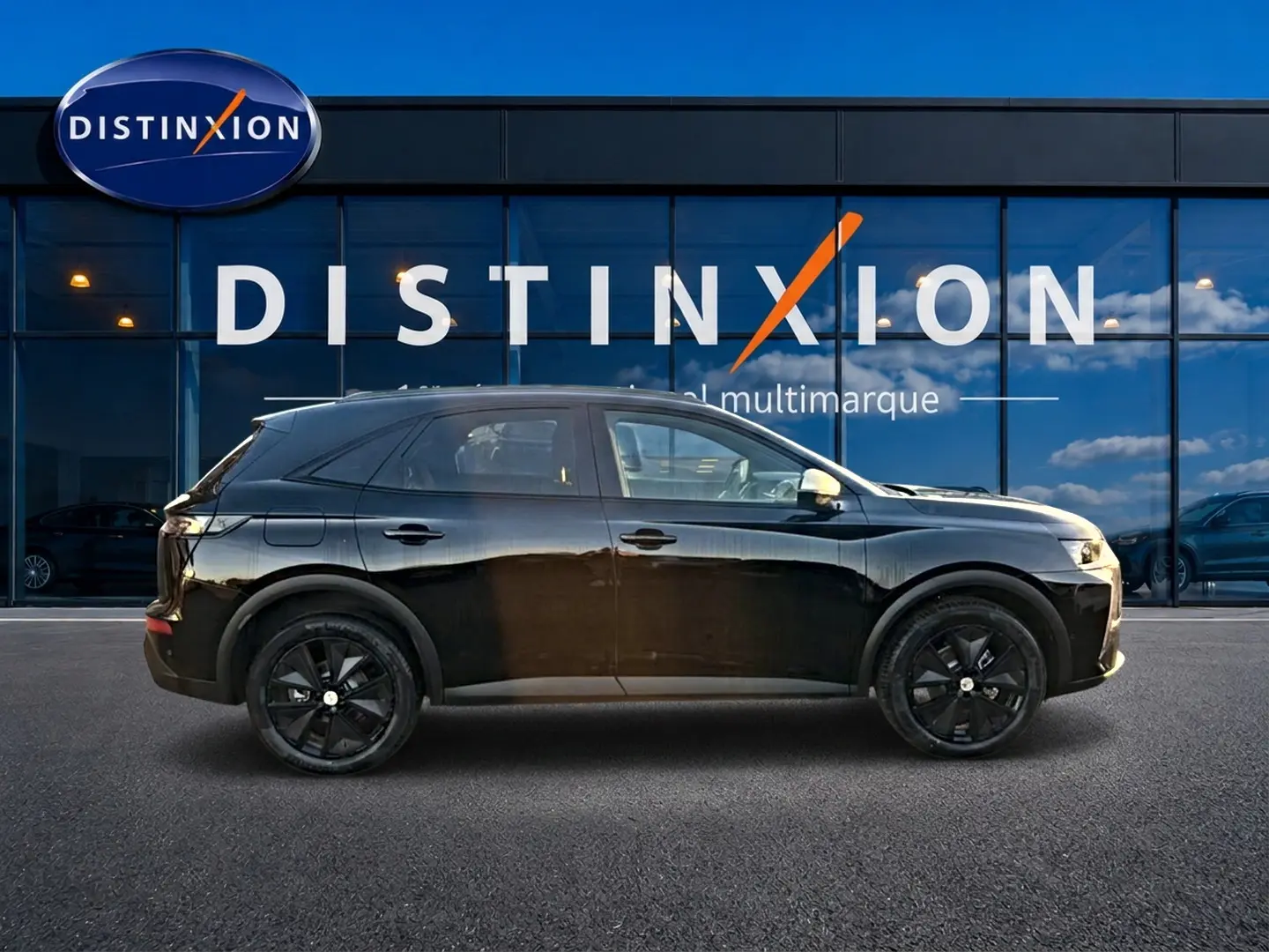 Vue de profil droit d'un DS7 noir 1.5 BlueHDi 130 Performance Line devant une vitrine Distinxion.