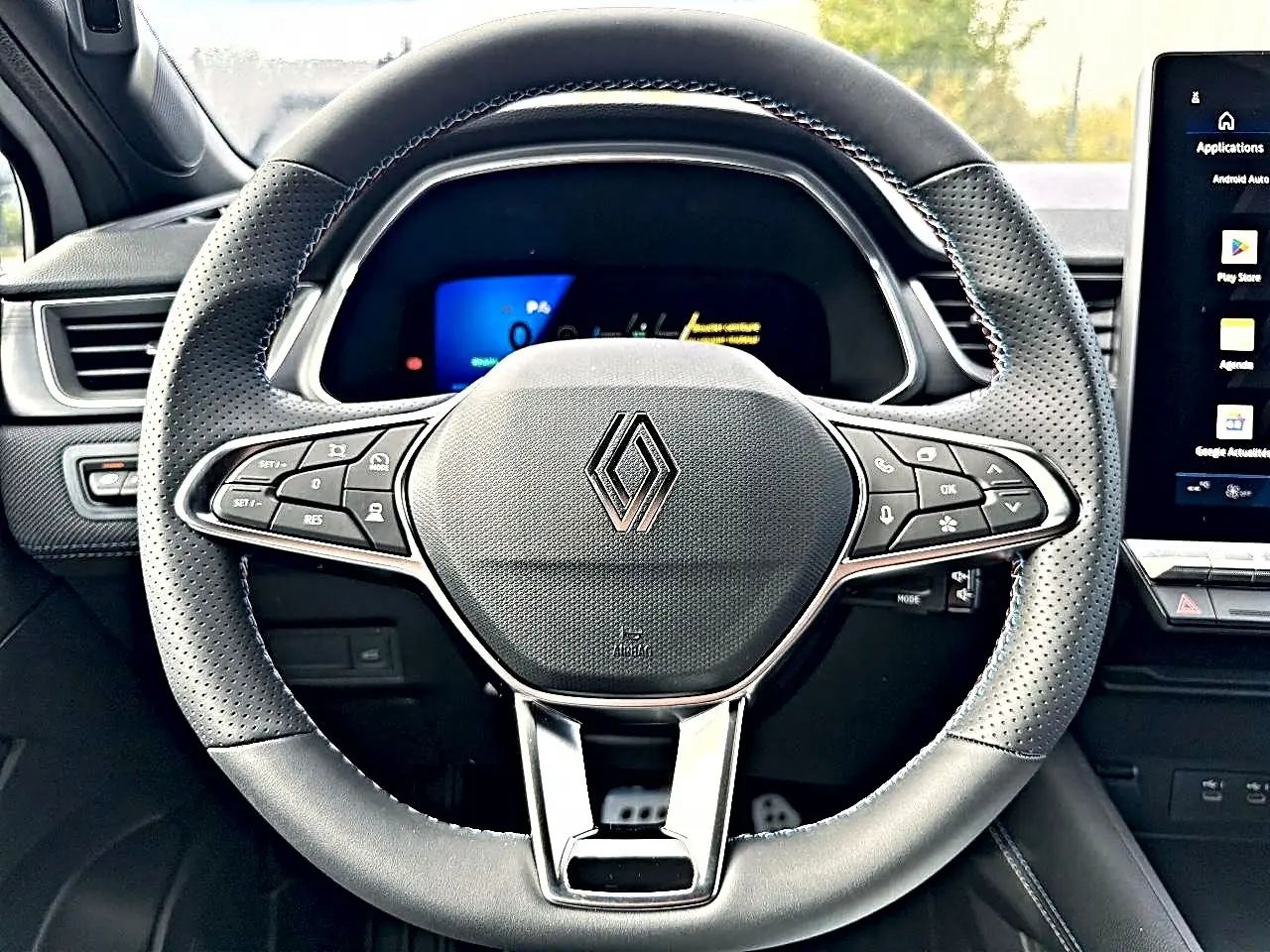 Vue rapprochée du volant noir perforé de la Renault Symbioz 2026 avec commandes multifonctions et logo central chromé.
