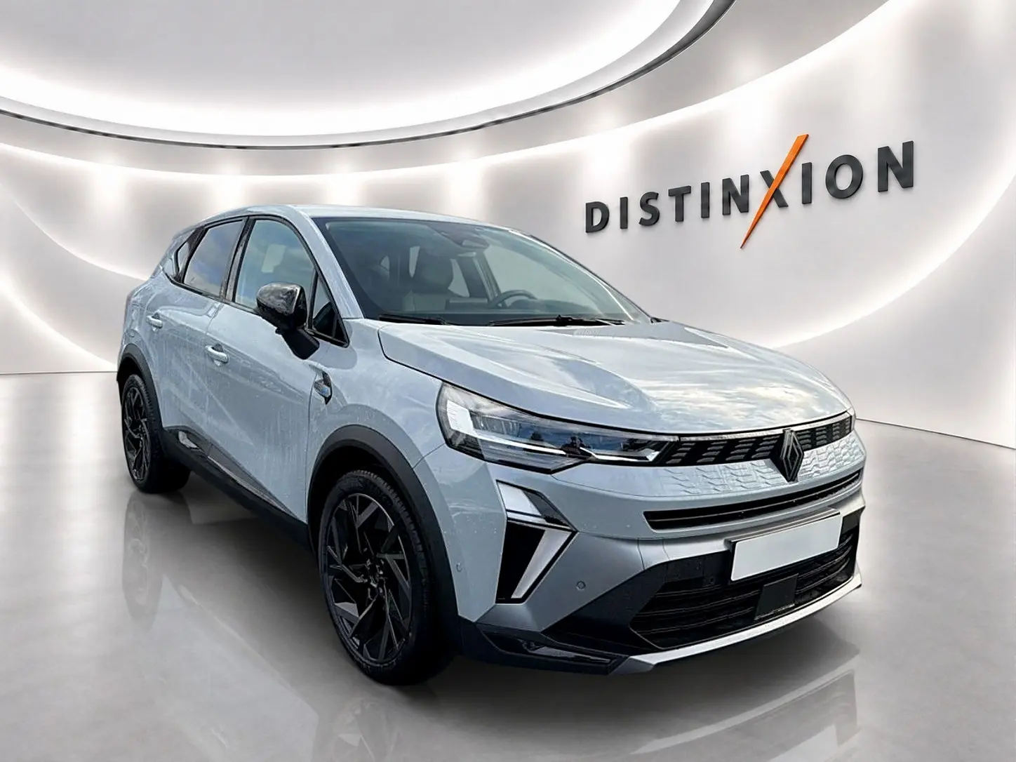Renault Symbioz gris rafale en 3/4 avant droit, avec jantes noires et calandre moderne dans un showroom lumineux.