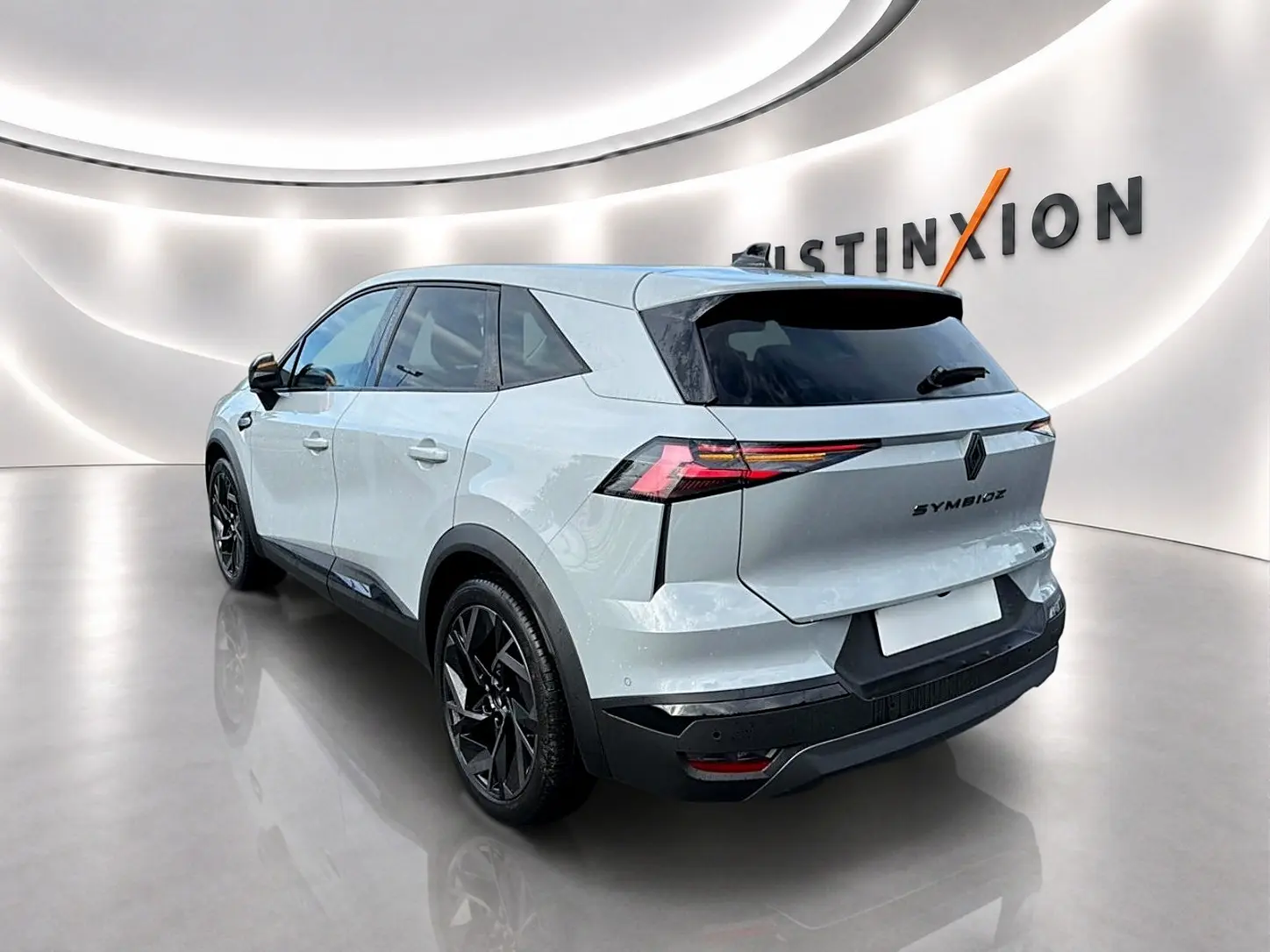 Vue 3/4 arrière droite du Renault Symbioz gris rafale avec feux arrière LED et jantes noires en showroom.