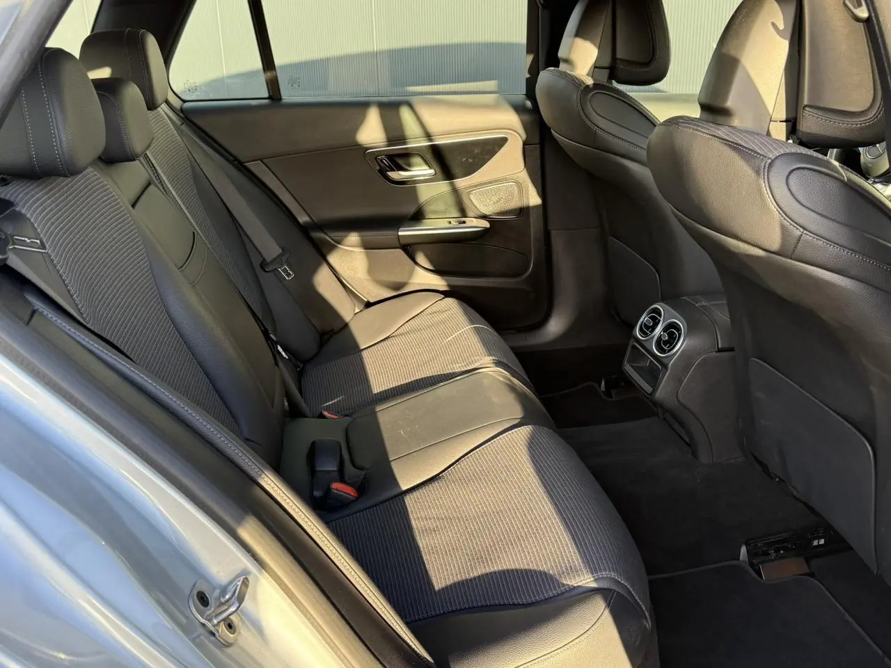 Vue intérieure arrière montrant les sièges noirs en cuir et tissu de la Mercedes Classe C Break 2023.