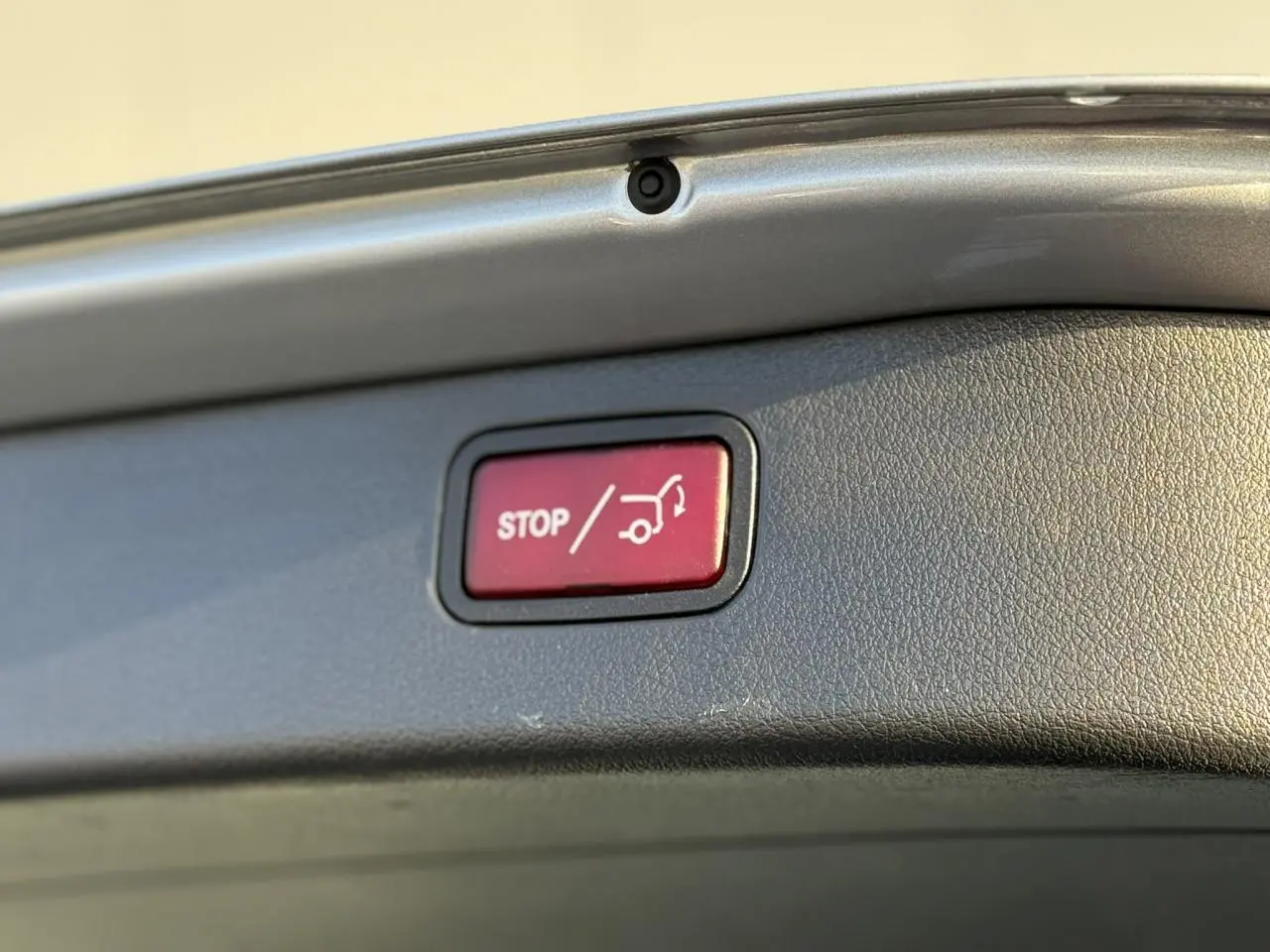 Bouton rouge stop pour fermeture électrique du hayon, visible sur le bord intérieur du coffre d'un Mercedes Classe C Break argent High-Tech.