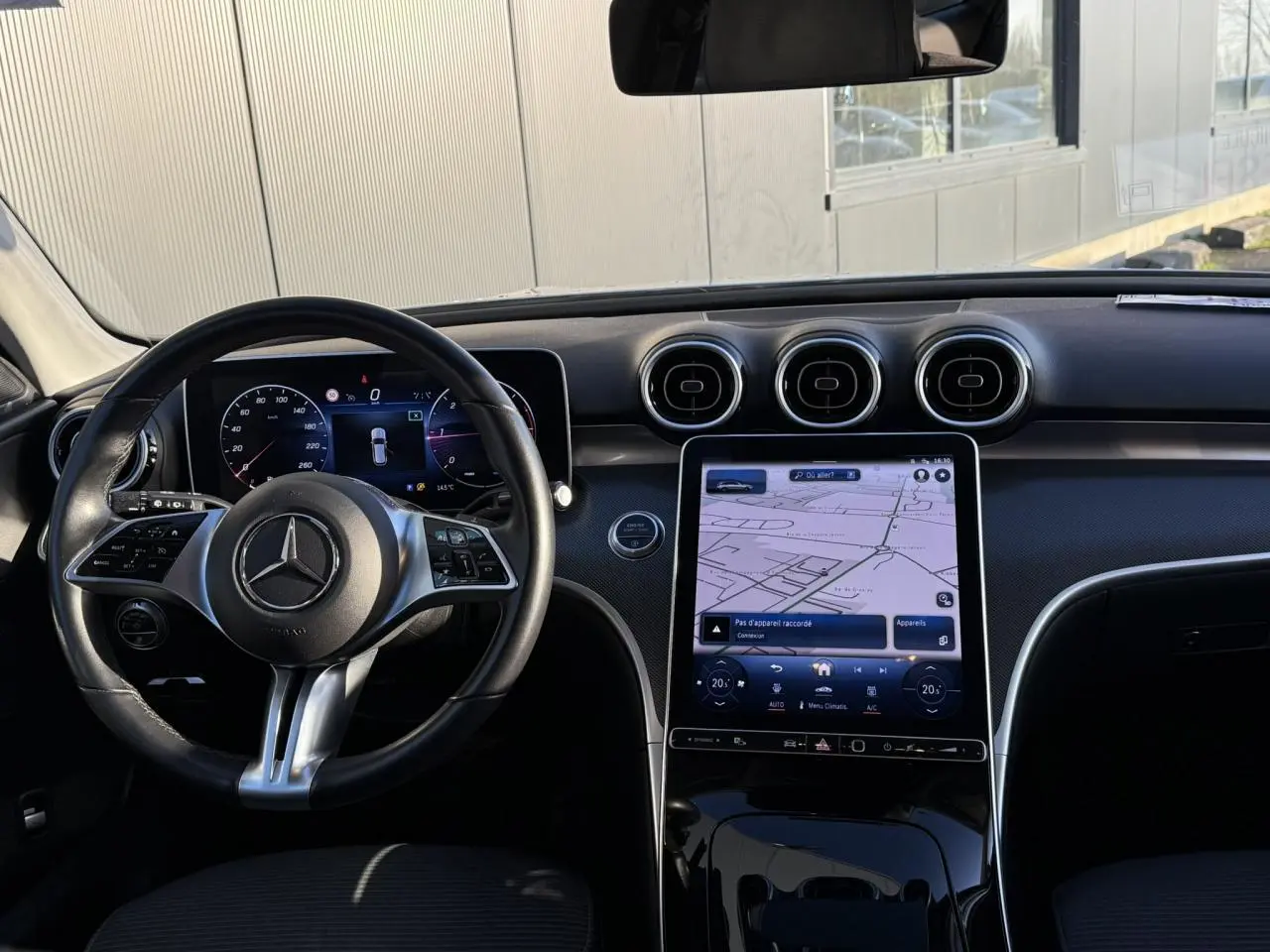 Vue intérieure côté conducteur du Mercedes Classe C Break argent, avec volant cuir et écran tactile de navigation.