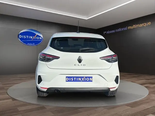 Vue arrière d'une Renault Clio V blanche, avec feux arrière Full LED et plaque Distinxion en intérieur showroom.