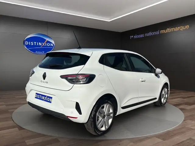 Renault Clio V blanche vue 3/4 arrière droit en intérieur, avec feux arrière Full LED et jantes alliage 16 pouces.