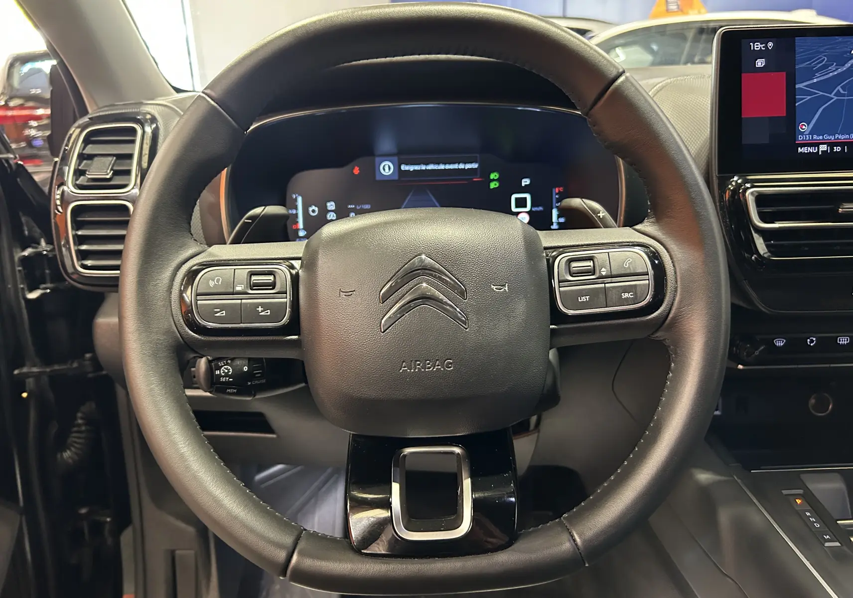Volant noir du Citroën C5 Aircross 2024 en vue frontale, avec commandes intégrées et tableau de bord numérique visible.