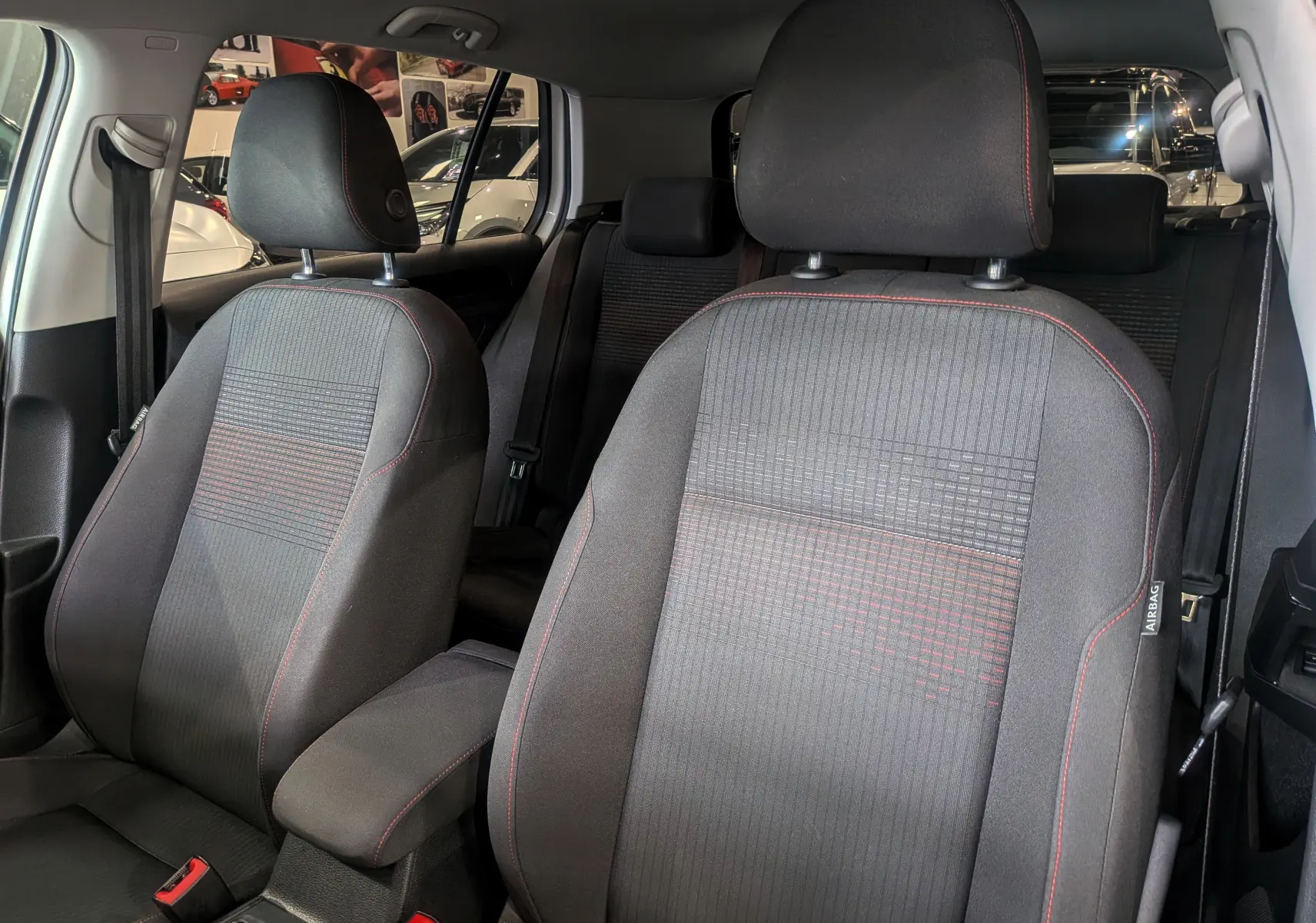 Gros plan sur les sièges avant en tissu noir avec surpiqûres rouges de la Volkswagen Golf VII TSI 125 CH Sound blanche.